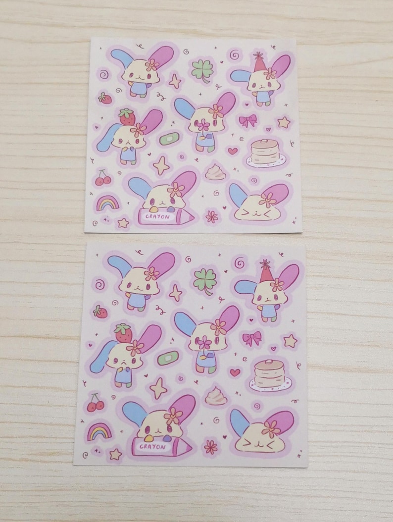 May include: Two sheets of stickers featuring a cartoon bunny with pink and blue ears, a flower, and a crayon. The stickers are on a pink background with other small cartoon images like hearts, stars, and cherries.