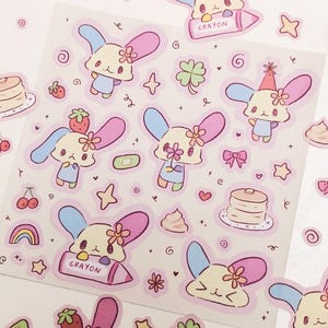 May include: A sheet of stickers featuring cute cartoon characters with pastel colors and various designs, including hearts, stars, rainbows, and a cupcake. The stickers are perfect for adding a touch of whimsy to journals, planners, and other items.