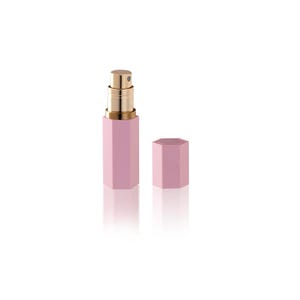Può includere: Un flacone di profumo esagonale rosa con un atomizzatore dorato e un tappo abbinato.