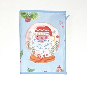 May include: A light blue zippered pouch featuring a snow globe design with Santa Claus inside. The snow globe is surrounded by snowflakes and Christmas trees. The pouch has a blue border and a zipper closure.