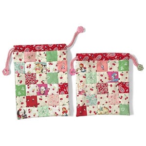 Peut inclure: Deux sacs à cordon patchwork avec un dessus en paisley rouge et un motif de cerises. Les sacs présentent des carrés avec différents motifs et illustrations d'animaux et de personnages. Le cordon est rose.