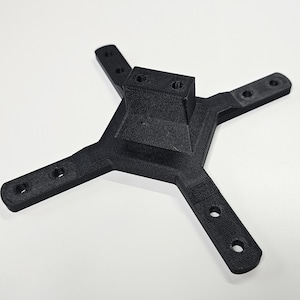 May include: A black, 3D-printed plastic component with a central square and four arms extending outwards. Each arm has two holes. The component is designed for structural support or mounting.