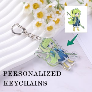 May include: A clear acrylic keychain featuring a cartoon character with green hair and blue clothing, holding a bamboo staff. The keychain is attached to a silver metal clasp. The text "PERSONALIZED KEYCHAINS" is below the keychain.
