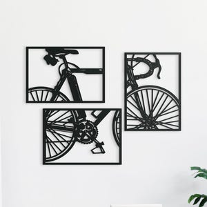 Könnte beinhalten: Ein Set aus drei Wandkunstobjekten aus schwarzem Metall mit Fahrradmotiv. Das Kunstwerk ist in drei rechteckige Rahmen unterteilt und zeigt den Sattel und Rahmen, das Vorderrad und den Lenker sowie die Pedale und das Kettenblatt eines Fahrrads.
