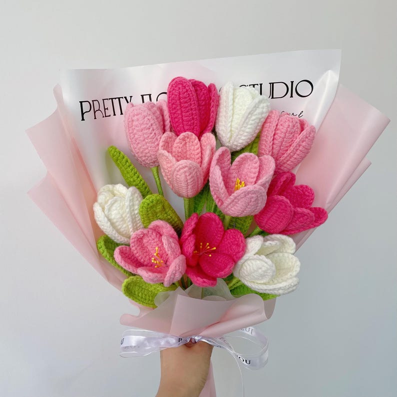 Pu&ograve; includere: Un mazzo di tulipani all'uncinetto rosa, bianco e rosa chiaro, avvolto in carta velina rosa con un nastro bianco. Il mazzo &egrave; etichettato "PRETTY FLOWER STUDIO".