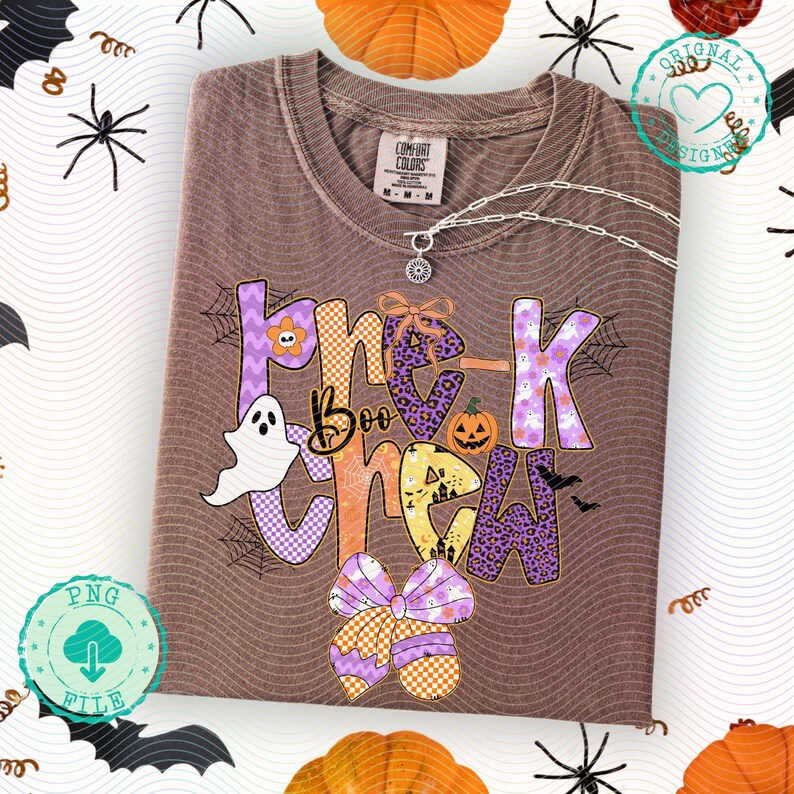 May include: Brown t-shirt with the text "Trick Boo Crew" in purple, orange, and yellow, featuring Halloween-themed graphics like a ghost, pumpkin, and bats. The shirt has a Comfort Colors tag and a silver necklace.