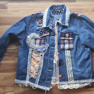 May include: A blue denim jacket with lace trim and patchwork details. The patchwork includes floral, plaid, and lace fabrics.