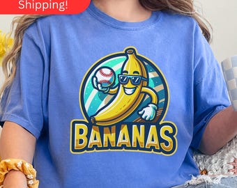 May include: A blue t-shirt with a cartoon banana wearing sunglasses and holding a baseball. The banana is wearing a white glove and the text "BANANAS" is printed below the banana.