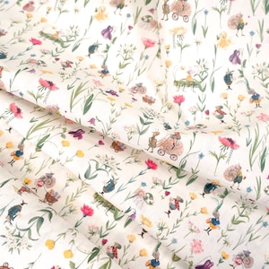 Könnte beinhalten: Weißer Stoff mit einem sich wiederholenden Muster aus kleinen, bunten Blumen und skurrilen Figuren. Die Figuren sind in Blau und Weiß gekleidet und tragen Körbe und fahren in Kutschen.