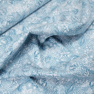 Könnte beinhalten: Blauer Stoff mit einem weißen Muschel- und Seesternmuster.