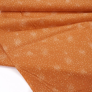 Peut inclure: Tissu orange à pois blancs. Le tissu est plié et le bord est visible.