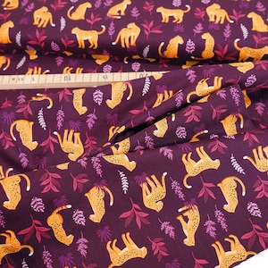 Peut inclure: Tissu violet avec un motif répété de léopards orange et de feuilles roses.