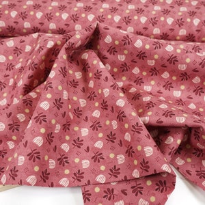 Könnte beinhalten: Nahaufnahme eines rosa Stoffes mit einem weißen und braunen Blumenmuster. Der Stoff ist in der Mitte gefaltet und hat ein Lineal in der linken unteren Ecke.