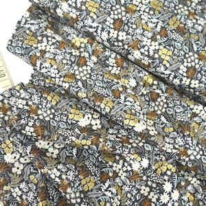 Könnte beinhalten: Nahaufnahme eines Stoffes mit Blumenmuster. Der Stoff ist dunkelgrau mit weißen, braunen und goldenen Blumen und Blättern.