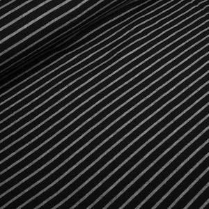 May include: Black and white striped fabric with a subtle sheen. The fabric has a diagonal pattern.