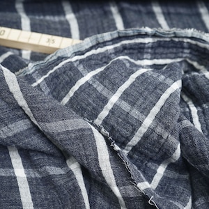 Könnte beinhalten: Nahaufnahme eines blau-weiß gestreiften Stoffes mit einer strukturierten Oberfläche. Der Stoff ist gefaltet und hat eine rohe Kante.