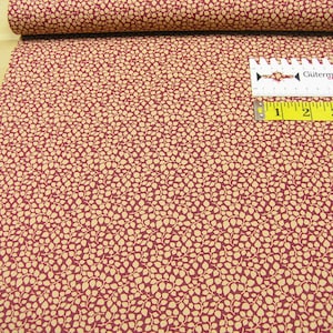 Può includere: Tessuto rosso con un motivo a foglie bianche. Il tessuto viene misurato con un metro a nastro.