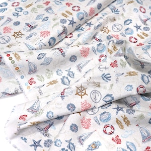 Könnte beinhalten: Weißer Stoff mit einem nautischen Muster. Der Druck zeigt Anker, Muscheln, Fische, Rettungsringe und Seesterne in Blautönen, Rot und Braun.