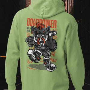 May include: A light green hooded sweatshirt featuring a graphic on the back of a stylized black boar with a red mohawk, a nose ring, and sneakers. The text "BOARDOWER" is printed in red above the character, with additional Japanese characters.