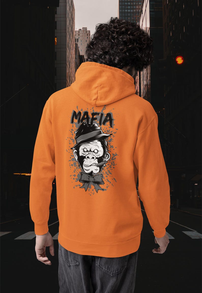 May include: An orange hooded sweatshirt featuring a graphic on the back of a gorilla wearing a black fedora hat and a bow tie with a cigar in its mouth. The word MAFIA is printed in black above the gorilla, surrounded by grey paint splatter.