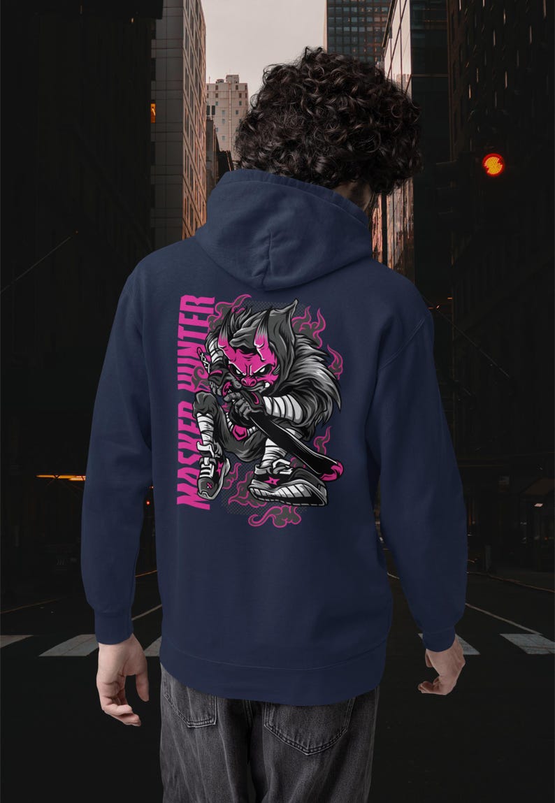 May include: A navy blue hooded sweatshirt featuring a graphic on the back of a stylized character with a pink mask and horns, holding a sword. The text "MASKED HUNTER" is printed vertically in pink next to the character, surrounded by pink flames.