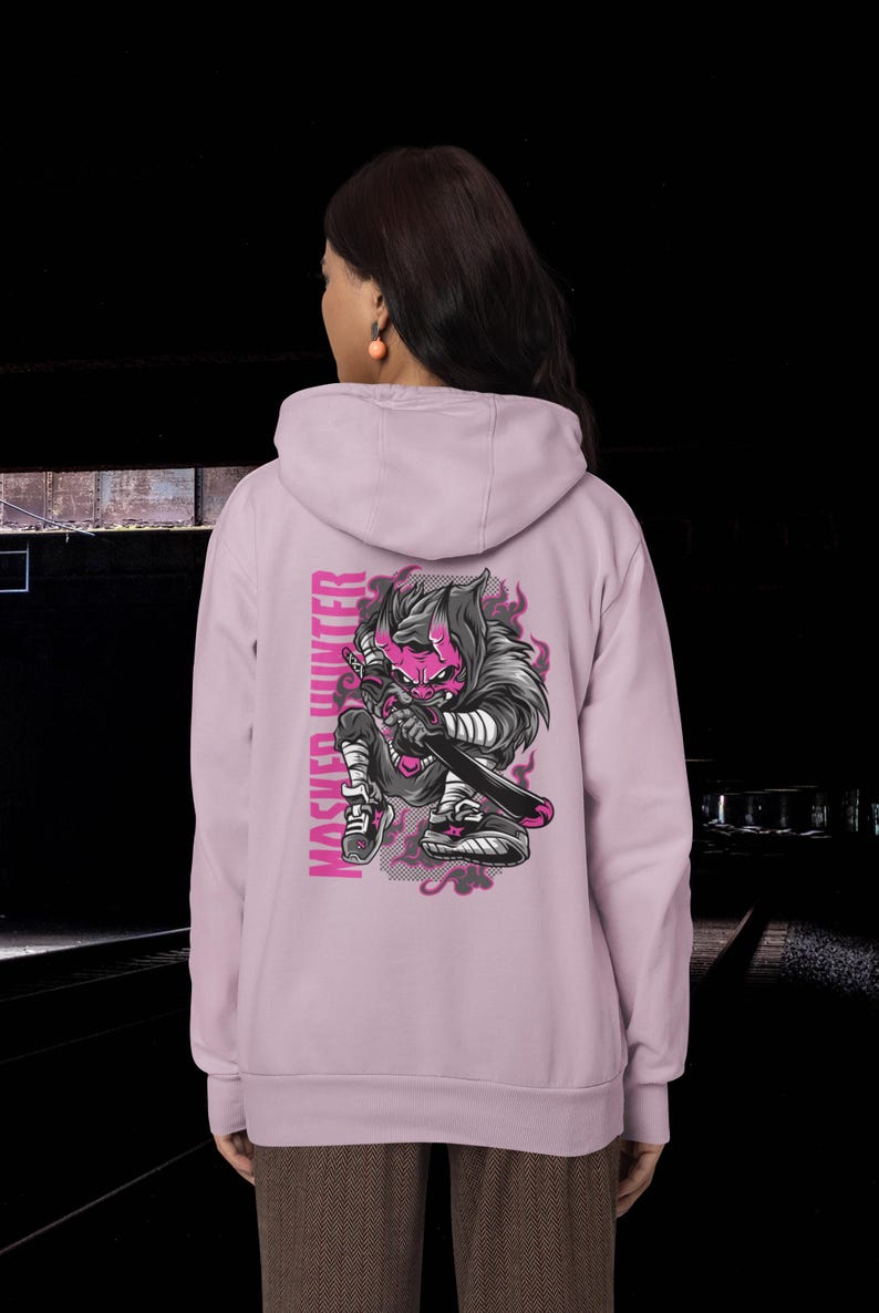 May include: A light purple hooded sweatshirt featuring a graphic on the back of a stylized creature with pink skin, horns, and dark fur, holding a sword. The text "MASKED HUNTER" is printed vertically in pink next to the illustration.