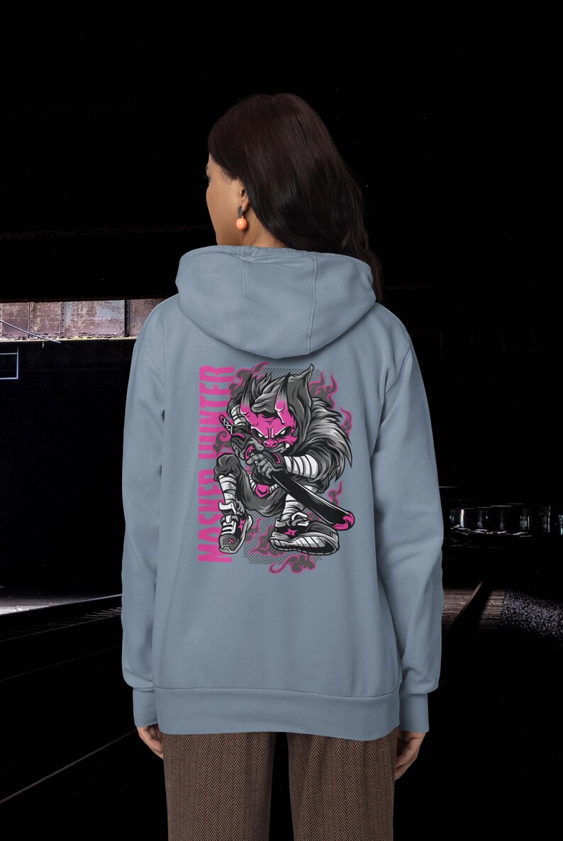 May include: A light blue hooded sweatshirt featuring a graphic on the back of a pink-skinned, horned character holding a sword. The character wears dark clothing and sneakers, with the text "MASKED HUNTER" printed vertically in pink next to it.