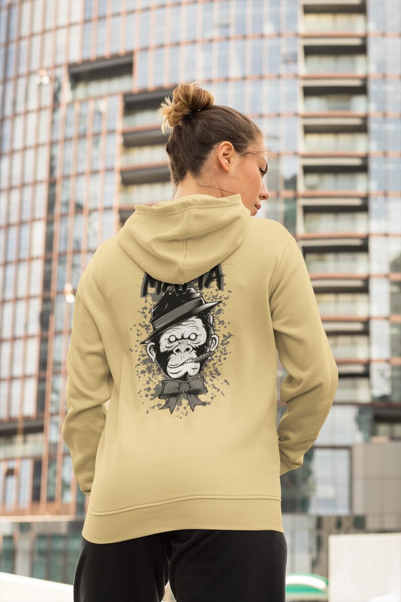 May include: A beige hooded sweatshirt featuring a graphic print on the back. The design displays a grayscale illustration of a gorilla wearing a fedora hat and a bow tie, with a cigar in its mouth. The word "MAFIA" is printed above the gorilla.