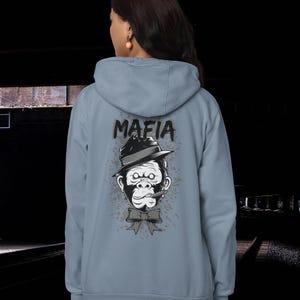 May include: A light blue hooded sweatshirt featuring a graphic on the back of a gorilla wearing a fedora hat and a bow tie with a cigar in its mouth. The word MAFIA is printed in black above the gorilla, surrounded by a gray splatter design.