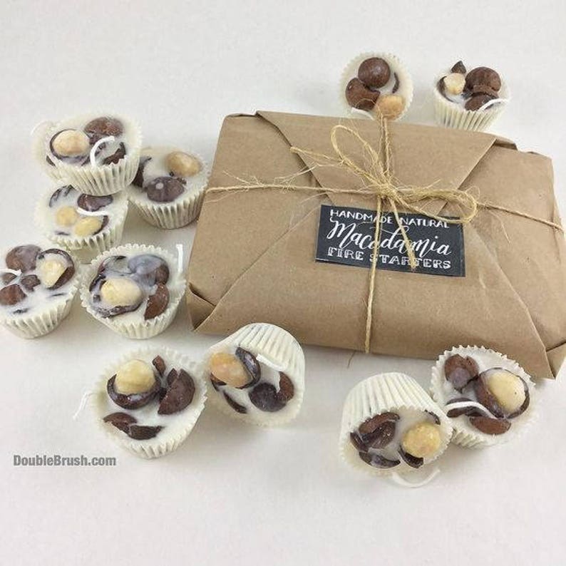 Pu&ograve; includere: Un pacchetto di accendini per il fuoco al cioccolato bianco con noci di macadamia, avvolto in carta marrone con un'etichetta che recita "Handmade Natural Macadamia Fire Starters".