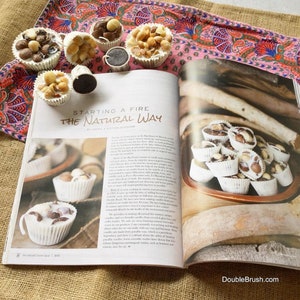 May include: A magazine page with the title "Starting a Fire the Natural Way" and a photo of white chocolate cups filled with macadamia nuts and chocolate pieces. The magazine page is on a pink and white floral fabric.