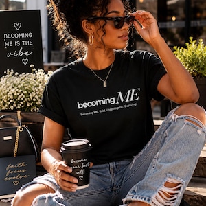 May include: A black short-sleeved t-shirt featuring the white text "becoming ME" and the subtitle "Becoming ME. Bold. Unapologetic. Evolving." paired with light blue distressed denim jeans and a black cup with the text "become your best self".