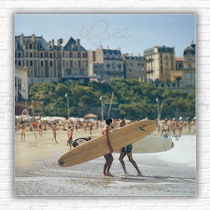 Impresión/póster de Peter Viertel de Slim Aarons: el autor y guionista Peter Viertel con su tabla de surf en la playa de Biarritz, Francia