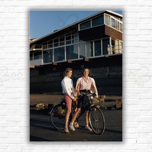 Stampa/manifesto del Slim Aarons La Jolla Club: due giovani donne condividono una bicicletta fuori dal La Jolla Beach & Tennis Club, San Diego, 1960.