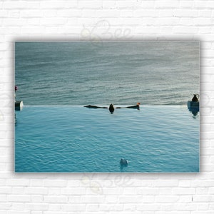 May include: A photograph of a swimming pool with a person swimming in the water. The pool is surrounded by a white wall and the water is a light blue color.