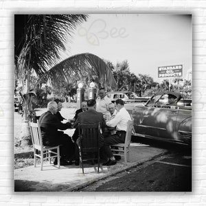 Eine Gruppe von Männern spielt Karten an einem Tisch neben einer Tankstelle in Palm Beach, Florida, 1955.