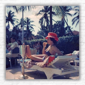Stampa/manifesto di Slim Aarons Leisure And Fashion: una donna guarda una sfilata di moda a bordo piscina al Colony Hotel, Palm Beach, Florida, 1961.