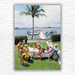 Stampa/poster della Slim Aarons Palm Beach Society - Il socialite Jim Kimberly e gli amici intorno alla sua auto sportiva bianca sulle rive del lago Worth, Florida