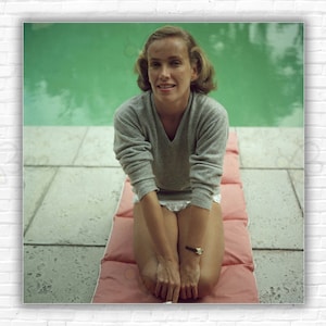 Stampa/Poster di Alice Topping di Slim Aarons - 1959: Alice Topping seduta su un materassino gonfiabile accanto a una piscina a Palm Beach, Florida.