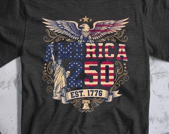 May include: Dark gray t-shirt featuring a patriotic design. The graphic includes an eagle, the Statue of Liberty, and the text "AMERICA 50 EST. 1776" in red, white, and blue. The design is vintage-inspired.