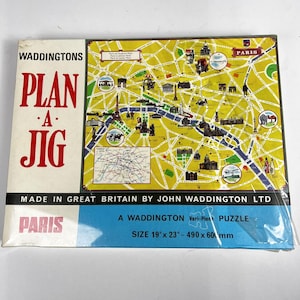 Pode incluir: Um puzzle vintage "Plan-A-Jig" da Waddingtons com um mapa de Paris. A caixa é branca com texto vermelho e um design de mapa amarelo. O puzzle mede 490 x 600 mm.