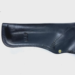 Peut inclure: Un &eacute;tui en cuir noir avec des coutures visibles et des rivets de couleur laiton. Le num&eacute;ro "474" est estamp&eacute; sur le c&ocirc;t&eacute;. L'&eacute;tui est con&ccedil;u pour contenir une arme &agrave; feu.