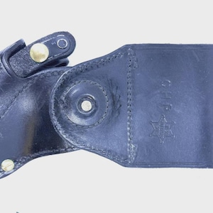 Peut inclure: Un &eacute;tui en cuir noir avec une fermeture &agrave; bouton-pression et des rivets dor&eacute;s. L'&eacute;tui pr&eacute;sente un motif cousu et un embl&egrave;me estamp&eacute;. Le texte "CHP" et un embl&egrave;me en &eacute;toile sont visibles sur l'&eacute;tui.