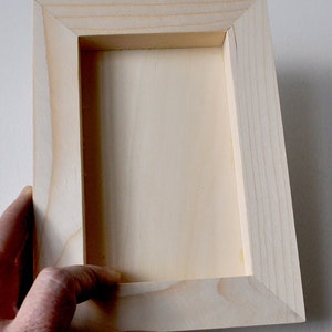 May include: A plain wooden frame with a light wood finish. The frame is empty and ready to be used for a picture or other artwork.