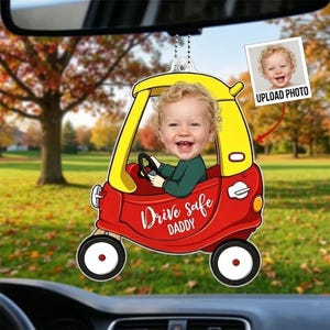 May include: A custom car-shaped hanging ornament featuring a red and yellow toy car with a child's photo integrated into the driver's seat. The side of the car is printed with the text Drive safe DADDY in white script and block lettering.