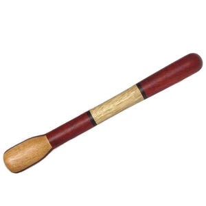 May include: A wooden muddler with a rounded handle and a flat, paddle-shaped end. The muddler features a combination of light and dark wood tones, with a reddish-brown handle and a natural wood-colored end. A thin black line separates the wood tones.
