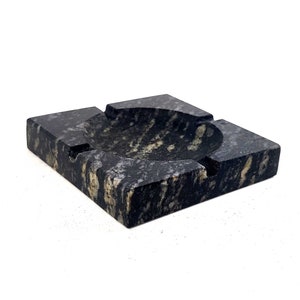 May include: A square black and white marble ashtray with a round depression in the center.