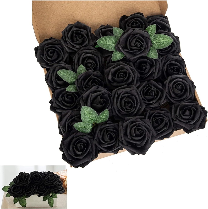 以下が含まれることがあります： 黒いシルクのバラの花の頭でいっぱいの箱。バラは緑の葉が散りばめられた円形に配置されています。