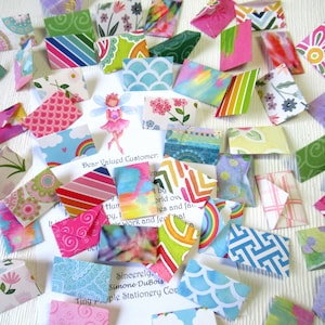 May include: A collection of colorful, patterned paper envelopes and notes. The envelopes feature various designs, including floral, geometric, and abstract patterns. A fairy illustration and text are visible on the notes. The text reads "Dear Valued Customer."