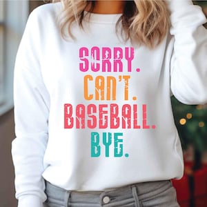 May include: White sweatshirt with a colourful graphic that reads "Sorry. Can't. Baseball. Bye."